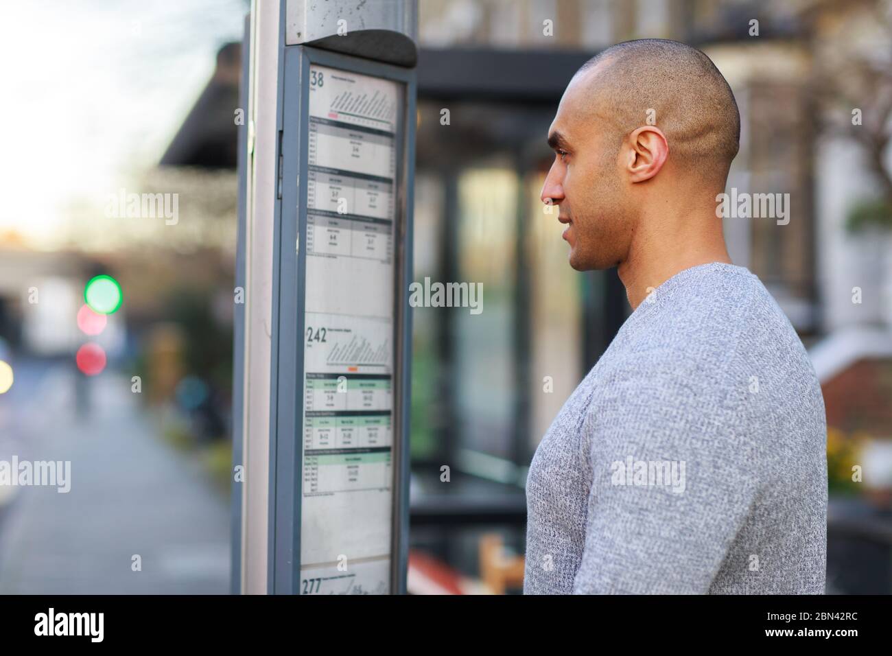 Junger Mann, der sich den Fahrplan des Busses anschaut Stockfoto