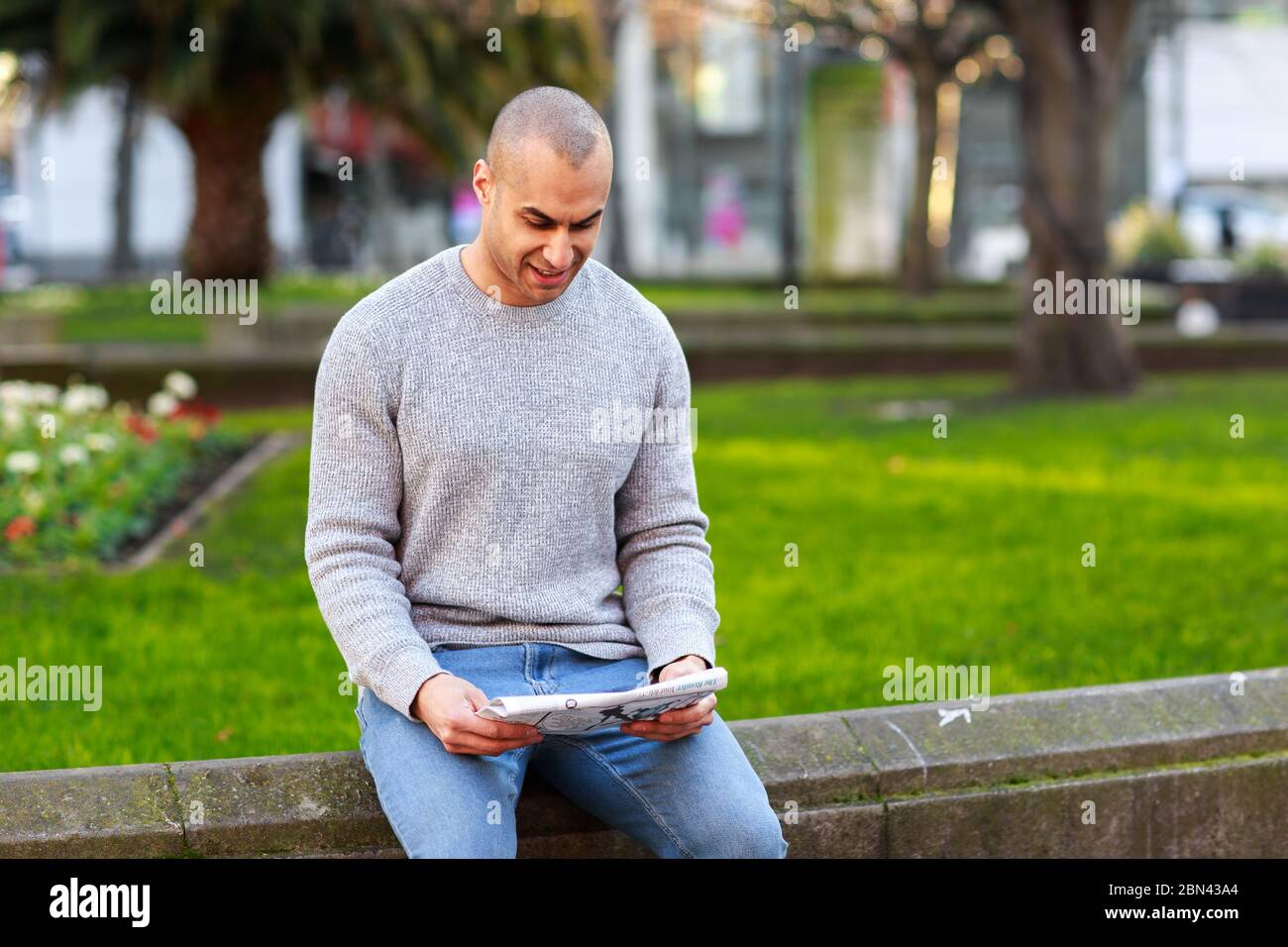 Ein junger Mann, der sich entspannt beim Lesen einer Zeitung ausruhen kann Stockfoto