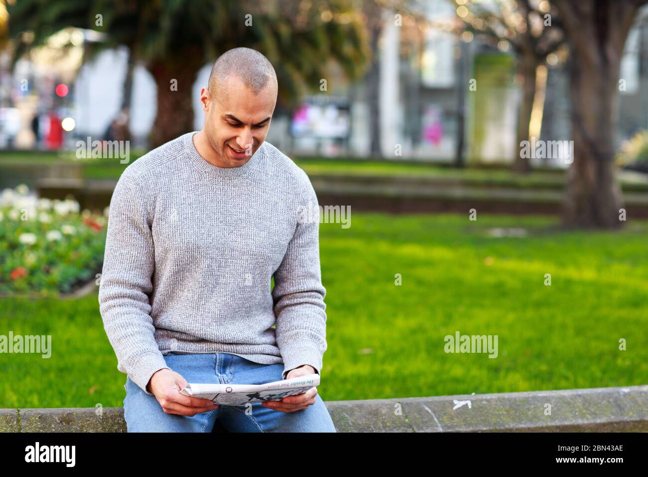 Junger Mann, der eine Zeitung liest Stockfoto