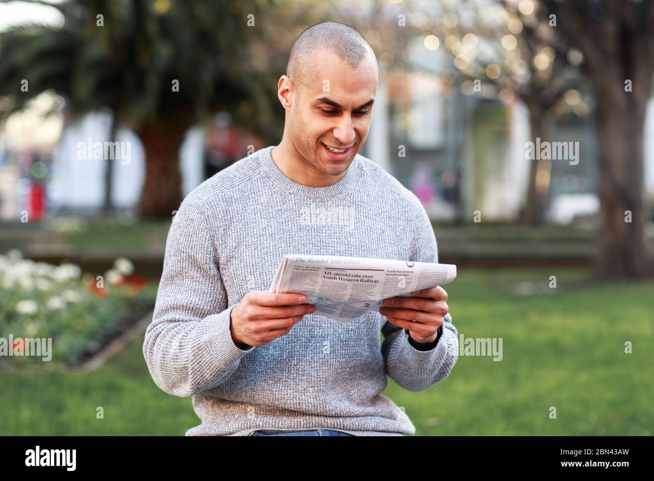 Junger Mann, der eine Zeitung liest Stockfoto