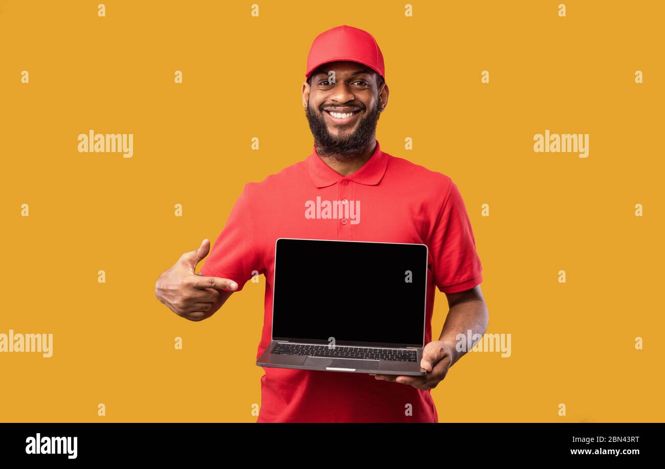 Courier Holding Laptop Mit Leerem Bildschirm Auf Gelbem Hintergrund, Mockup Stockfoto