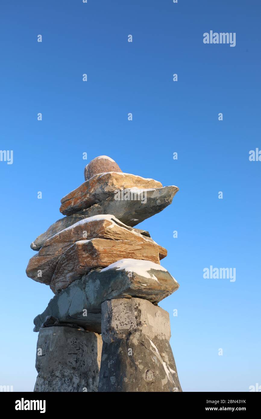 Seitenprofil eines Inuksuk oder Inukshuk mit blauem Himmel auf der Spitze eines Hügels in der Gemeinde Rankin Inlet, Nunavut, Kanada Stockfoto