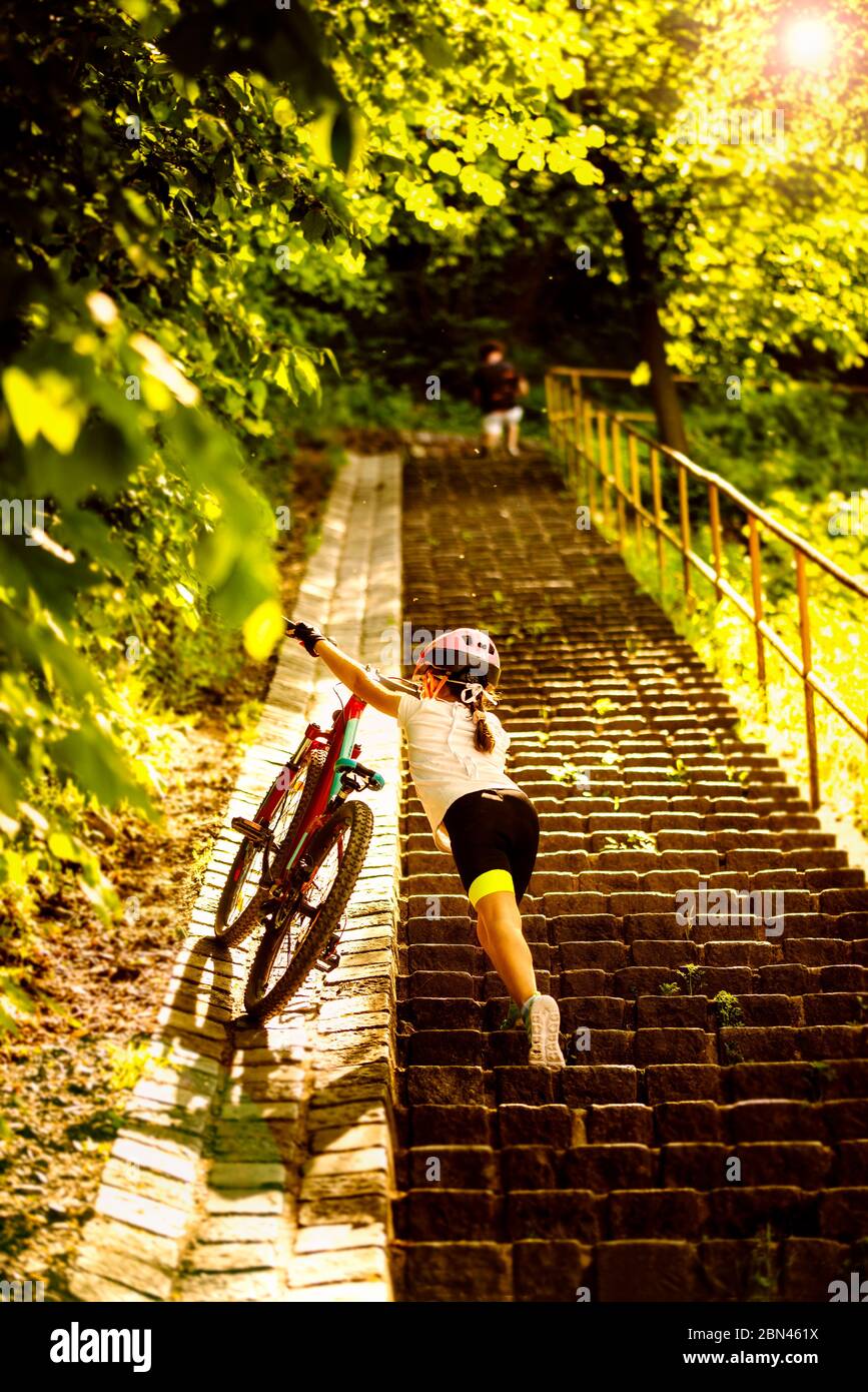 9 Jahre Mädchen bringen für die Treppe ihr Fahrrad Am sonnigen Tag Stockfoto