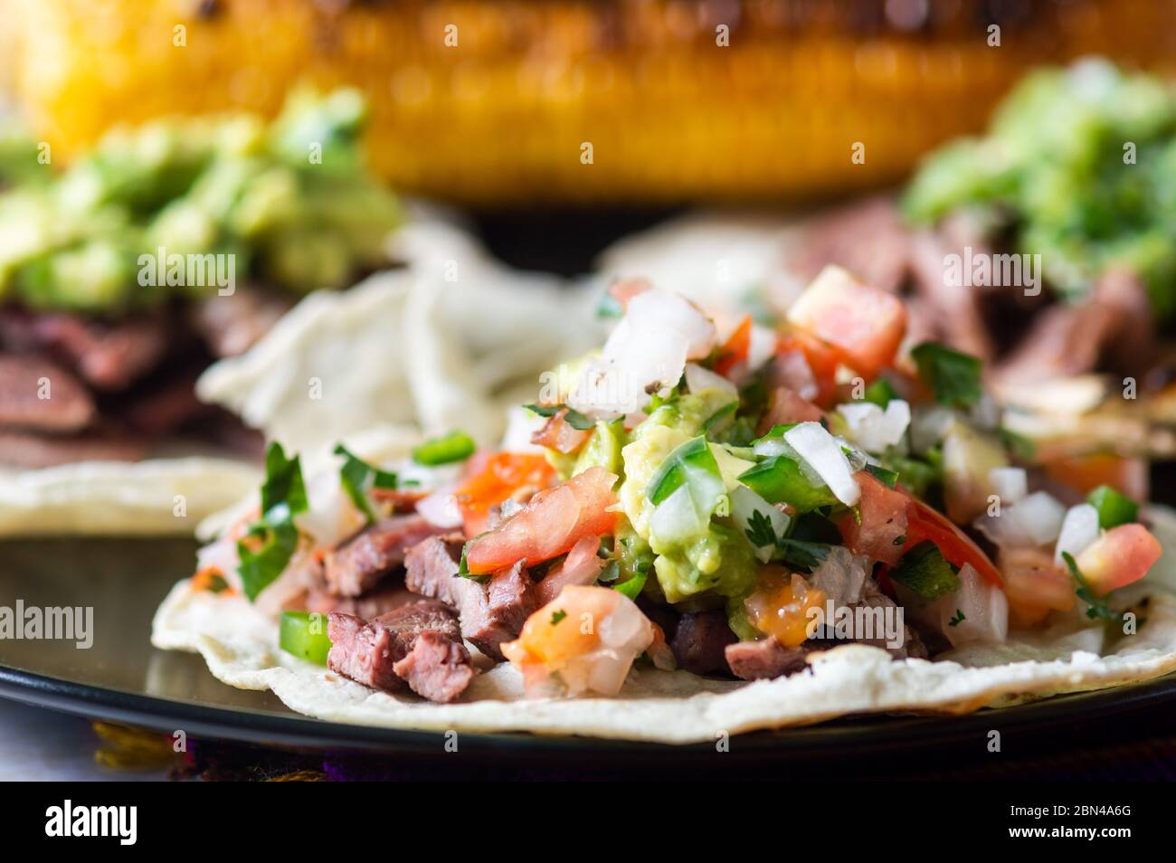 Mexikanische Carne Asada Tacos, buchstäblich gegrilltes Fleisch Tacos. Es handelt sich um gehacktes gegrilltes Rindfleisch, das auf weichen Maiskolben mit Salsa verde und Pico de ga serviert wird Stockfoto