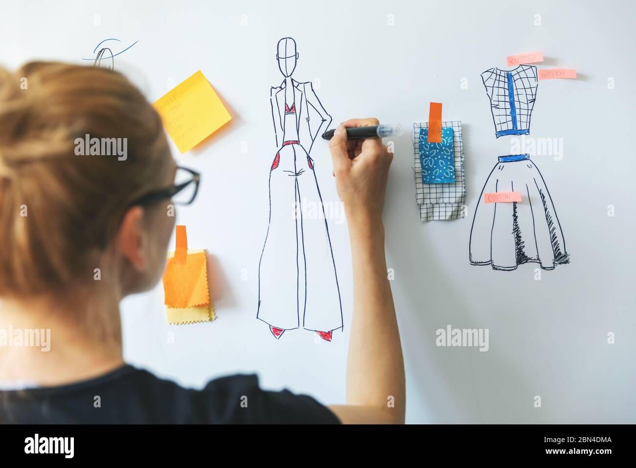 Modedesignerin skizziert neue Bekleidungskollektion auf Whiteboard Stockfoto