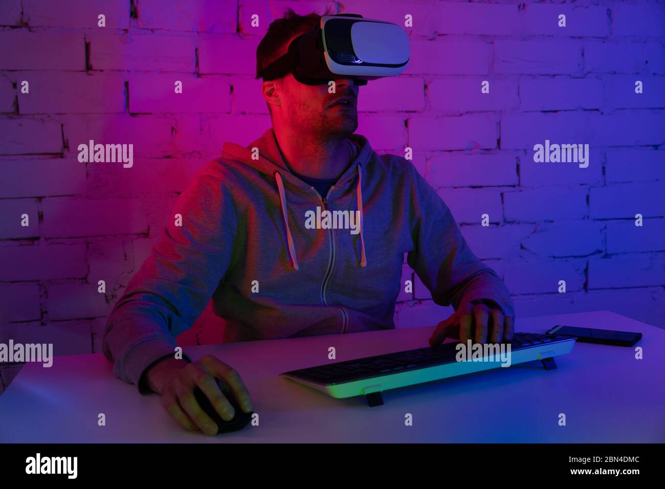 VR-Gaming - Mann spielt Videospiele mit Virtual Reality-Headset im Raum mit Neonbeleuchtung Stockfoto