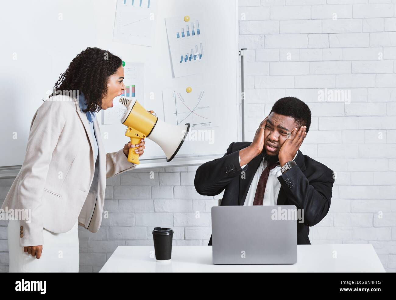 Emotionale Dame Chef mit Megaphon schreit auf männlichen Mitarbeiter am Arbeitsplatz Stockfoto
