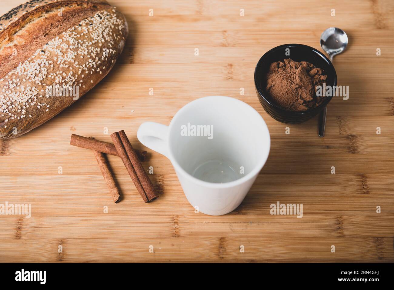Flach auf Holztisch aus schwarzem Becher mit Kakao, Brot und Zimt legen Stockfoto
