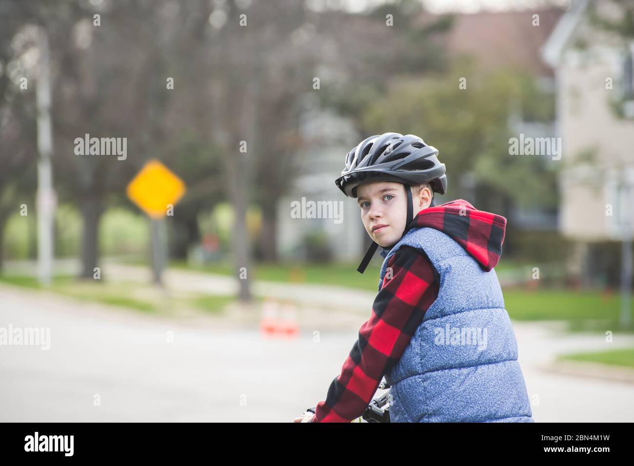 Porträt eines Kindes, das an einem kalten Tag einen Fahrradhelm trägt, mit Hoodie und Weste Stockfoto