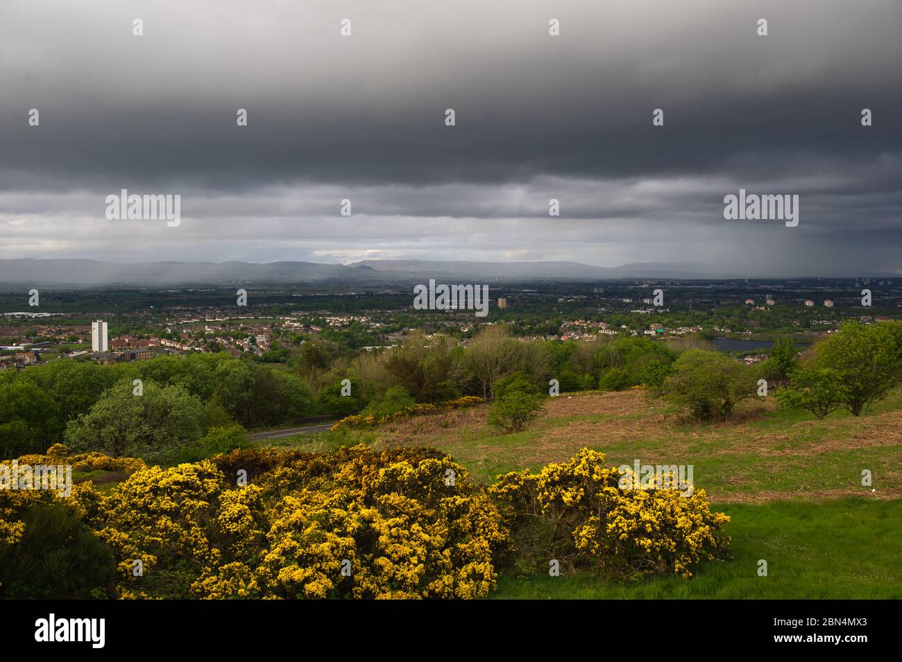 Glasgow, Schottland, Großbritannien. Mai 2020. Bild: Blick nach Norden über Glasgow mit den Campsie Fells im Hintergrund, umgeben von einem Schleier aus Regen und dunklen Wolken mit einer Wolkenbasis von etwa 2.500 m. Kühle Abendtemperaturen als Explosion der arktischen Luftmasse steigt aus dem Norden mit Steadregen und starken, aber kurzen Sonnenstrahlen durch Lücken in der Wolke. Quelle: Colin Fisher/Alamy Live News Stockfoto