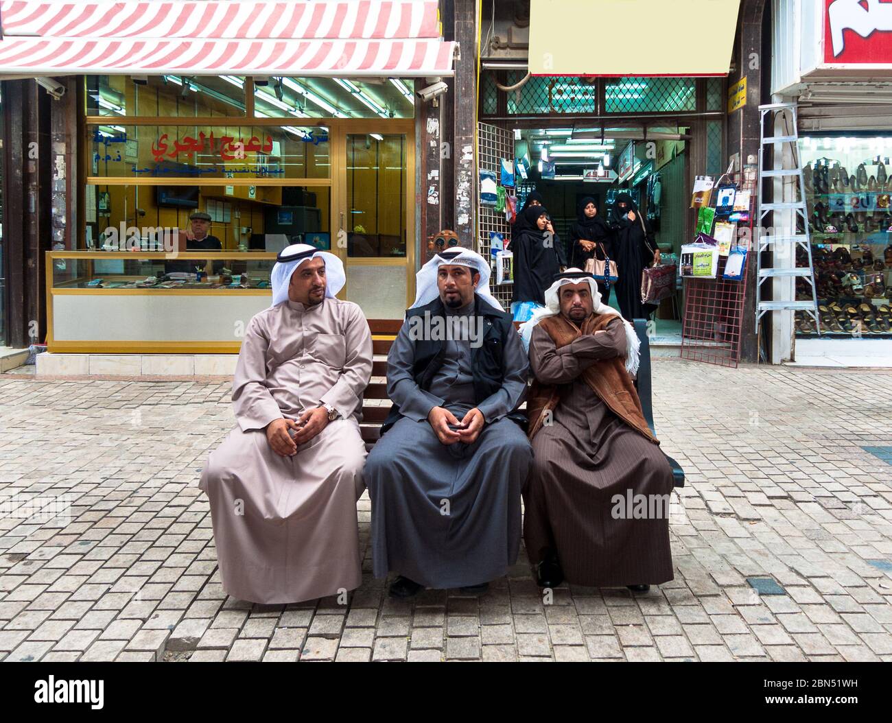 Kuwait-Stadt, Kuwait: Drei arabische Männer sitzen in der Nähe in traditioneller Kleidung Stockfoto