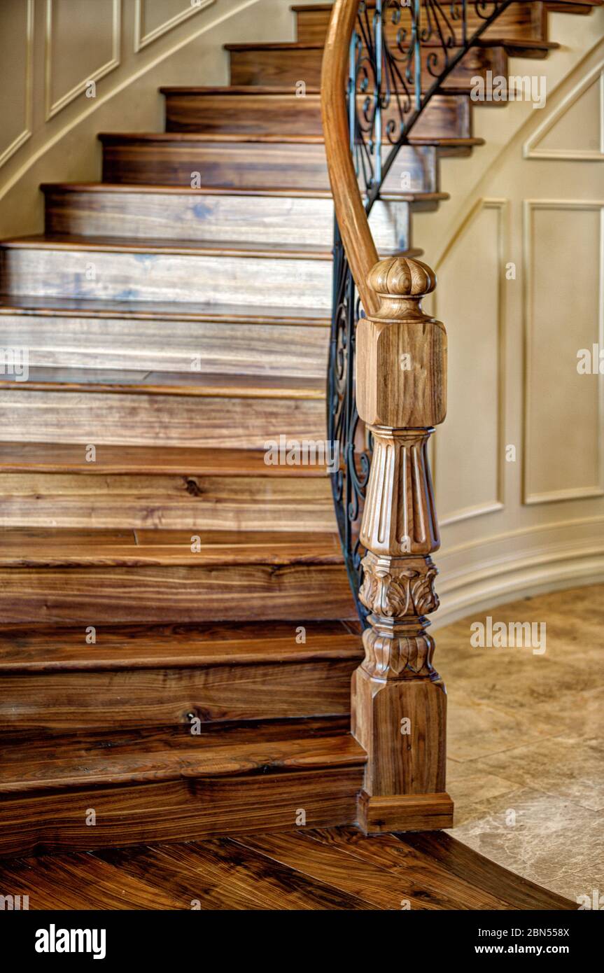 Ein schwarzer Walnuss-Newel-Pfosten am unteren Ende einer großen Treppe. Stockfoto