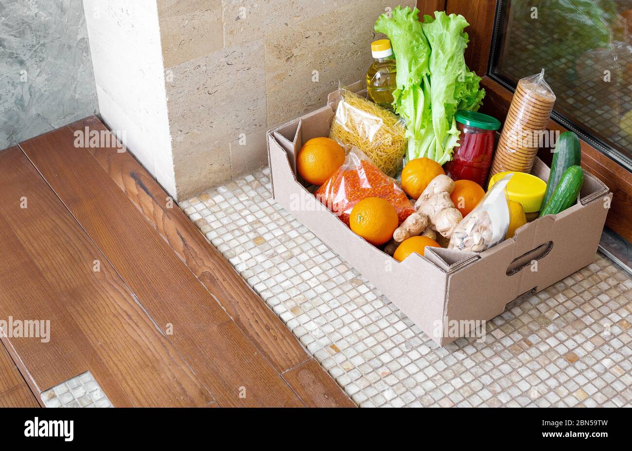 Spendenbox mit Nahrung während der covid Quarantäne. Die Lieferung der Food Box liegt direkt vor der Tür. Kontaktlose Zustellung nach Hause, sicheres Einkaufen Stockfoto