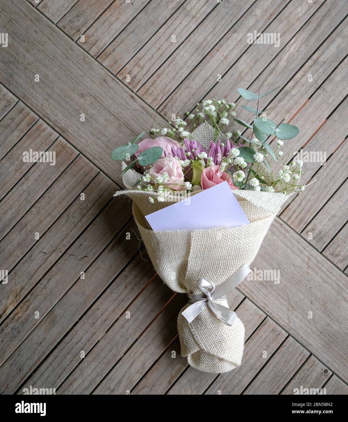 Handblumenstrauß besteht aus Chrysantheme, Rosen und grünen Blättern. Mit einer leeren Karte für Text. Stockfoto