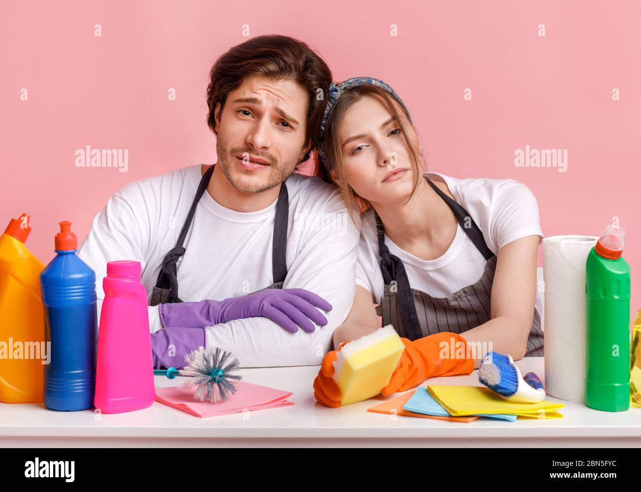 Unangenehme Hausarbeit. Unzufrieden Paar am Tisch mit vielen Waschmitteln sitzen Stockfoto