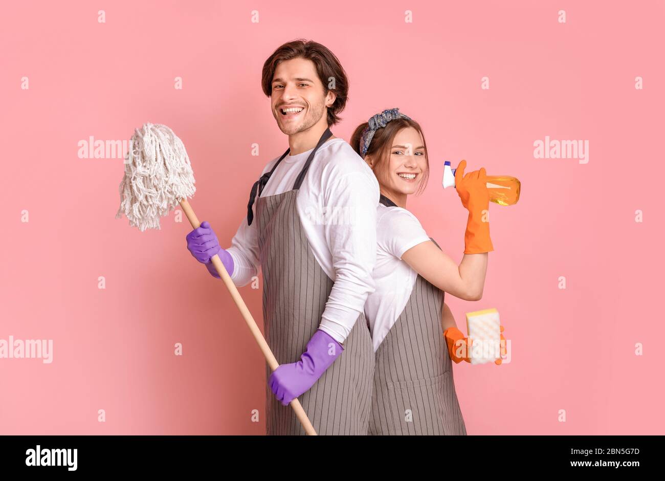 Professioneller Reinigungsservice. Lächelnder Mann Und Frau Mit Haushaltsgeräten In Den Händen Stockfoto