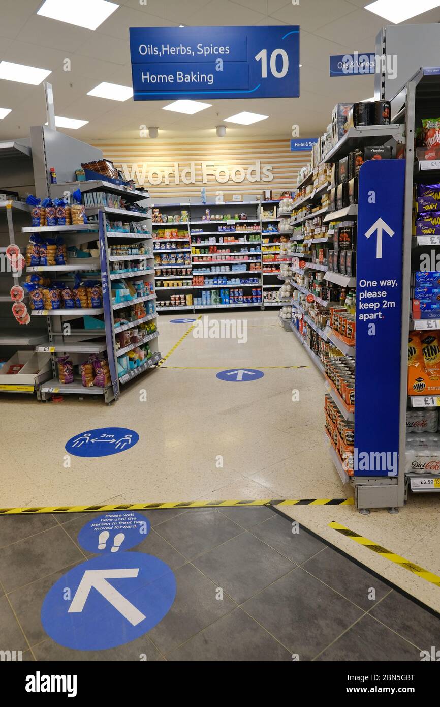 Bodenmarkierungen und Gefahrenbänder kennzeichnen Bereiche in einem Tesco-Geschäft, die Kunden bei der sozialen Distanz während der Sperrung helfen. Stockfoto