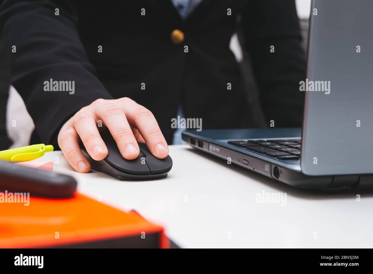 Weibliche Hand arbeitet an der Maus Nahaufnahme mit Laptop und Notizen im Home Office, Remote-Arbeit Stockfoto