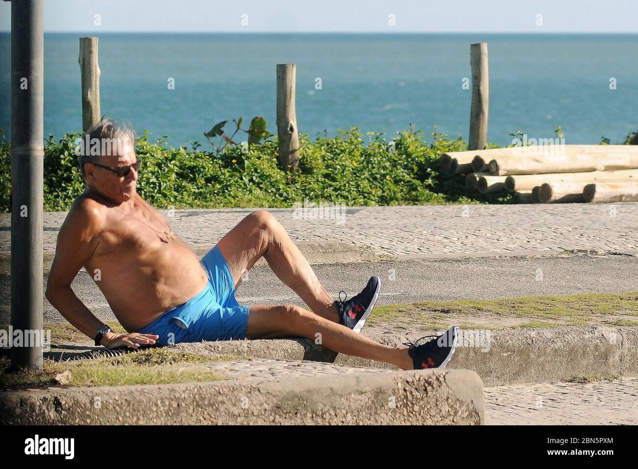 Rio de Janeiro, Brasilien, 11. Mai 2020. Älterer Mann ohne Schutzmaske während der COVID-19 Pandemie stolpert er und fällt auf den Bürgersteig Boden Stockfoto