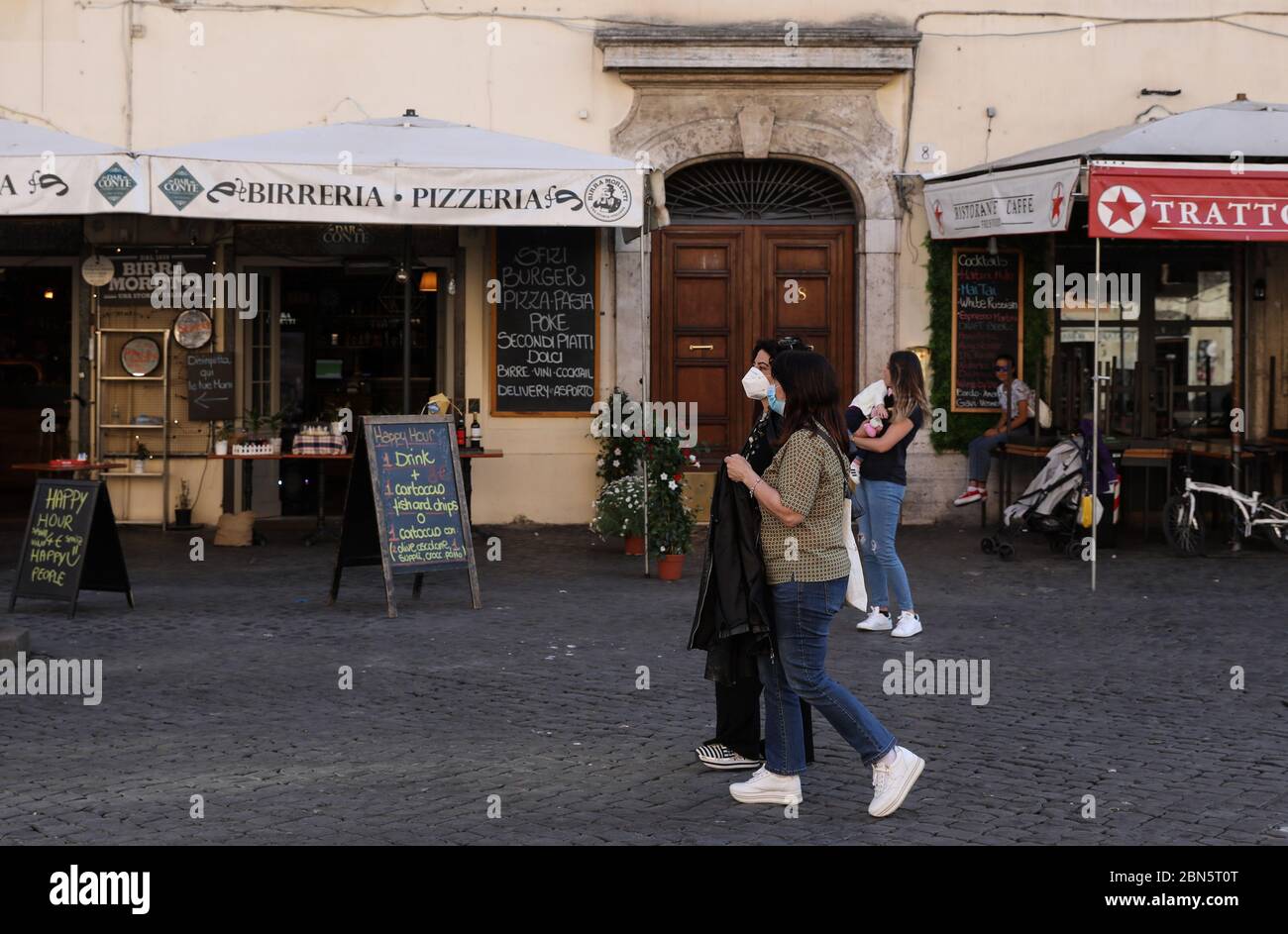 Rom, Italien. Mai 2020. Menschen mit Gesichtsmasken laufen an Restaurants vorbei, die am 12. Mai 2020 in Rom, Italien, zum Mitnehmen wiedereröffnet wurden. DAZU: 'Italien COVID-19 Fälle fallen, da Land sich auf wirtschaftlichen Niedergang eingelassen hat' Quelle: Cheng Tingting/Xinhua/Alamy Live News Stockfoto