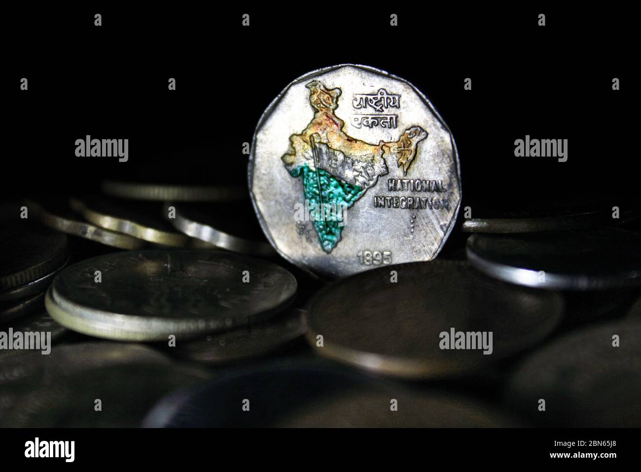 Zwei Rupien-Münzen Indiens isoliert auf schwarzem Hintergrund. Karte von Indien als Symbol der indischen nationalen Integration in den indischen Münzen dargestellt. Stockfoto