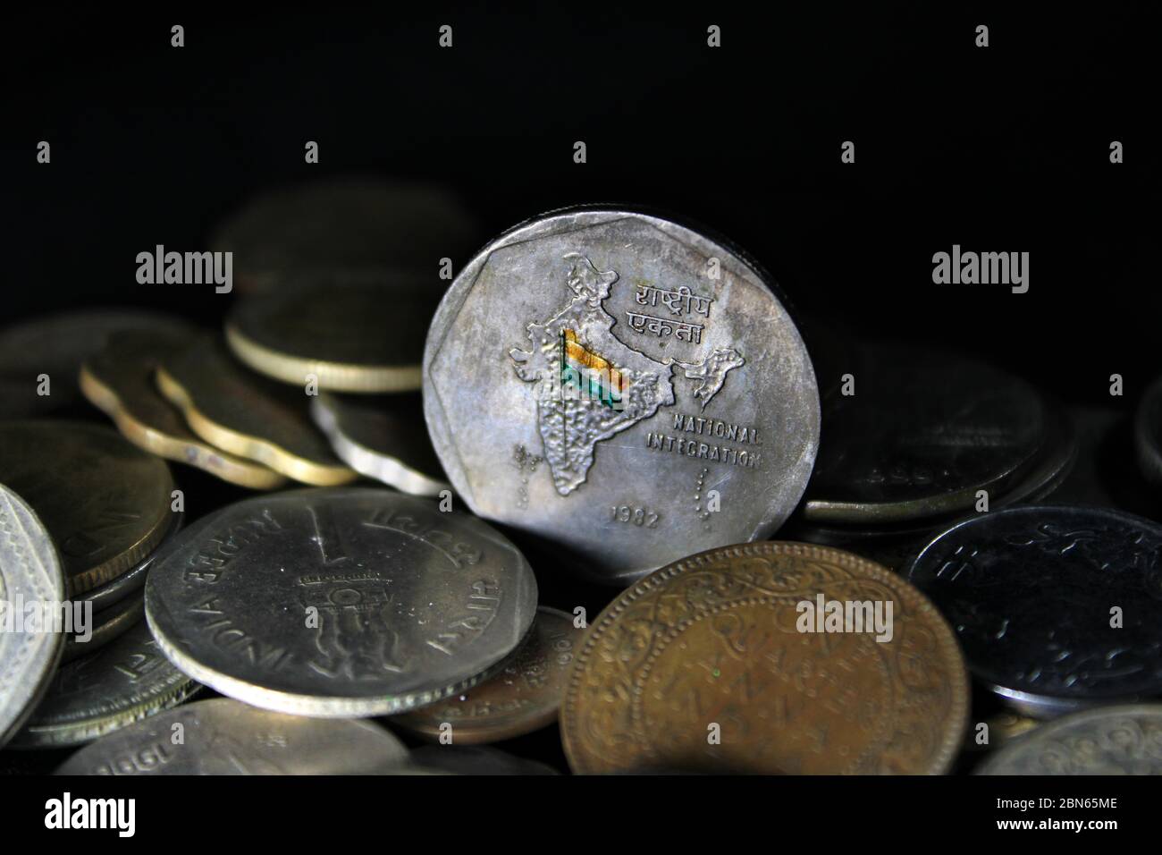 Zwei Rupien-Münzen Indiens isoliert auf schwarzem Hintergrund. Karte von Indien als Symbol der indischen nationalen Integration in den indischen Münzen dargestellt. Stockfoto