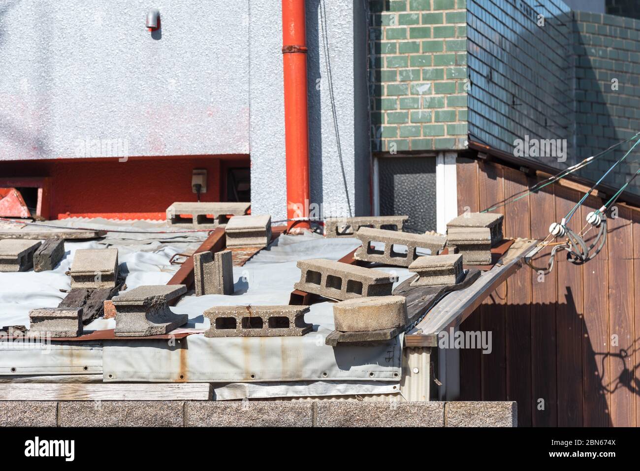 Betonhohlblöcke auf dem Dach eines Hauses, um vor starkem Wind zu schützen. Stockfoto