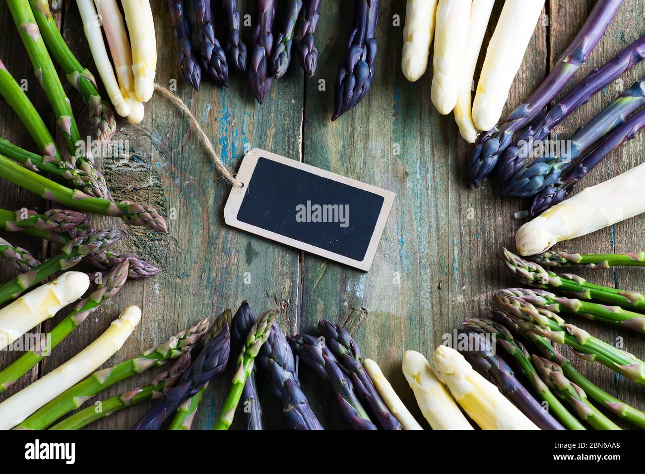 Rahmen aus frisch selbst angebautem natürlichen Bio-Spargel und Kreidetafel für Botschaft auf Holzhintergrund. Stockfoto