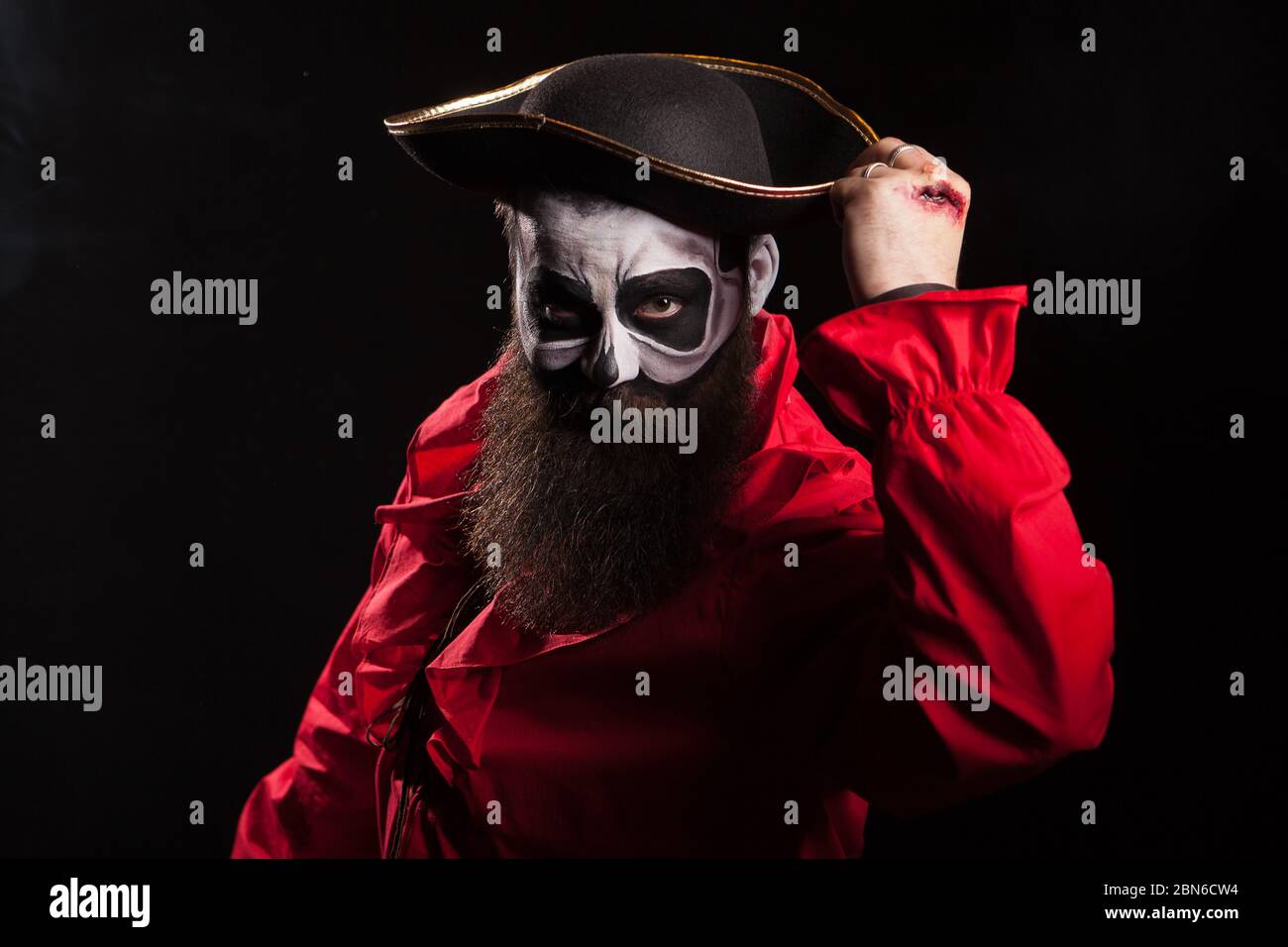 Bärtiger und gruseliger mittelalterlicher Pirat mit Blut auf seinen Händen auf schwarzem Hintergrund. Halloween Verkleidung. Stockfoto
