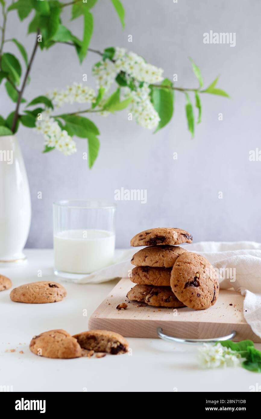 Ein Stapel von Schokoladenstückchen mit Milch und einigen frühlingshaften blühenden Zweigen im Hintergrund Stockfoto