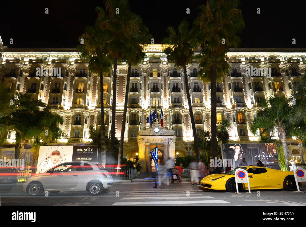 Blick auf das InterContinental Carlton Hotel bei Nacht mit dem gelben Ferrari 458 vor dem Hotel. Croisette in Cannes, Cote d'Azur, Frankreich Stockfoto