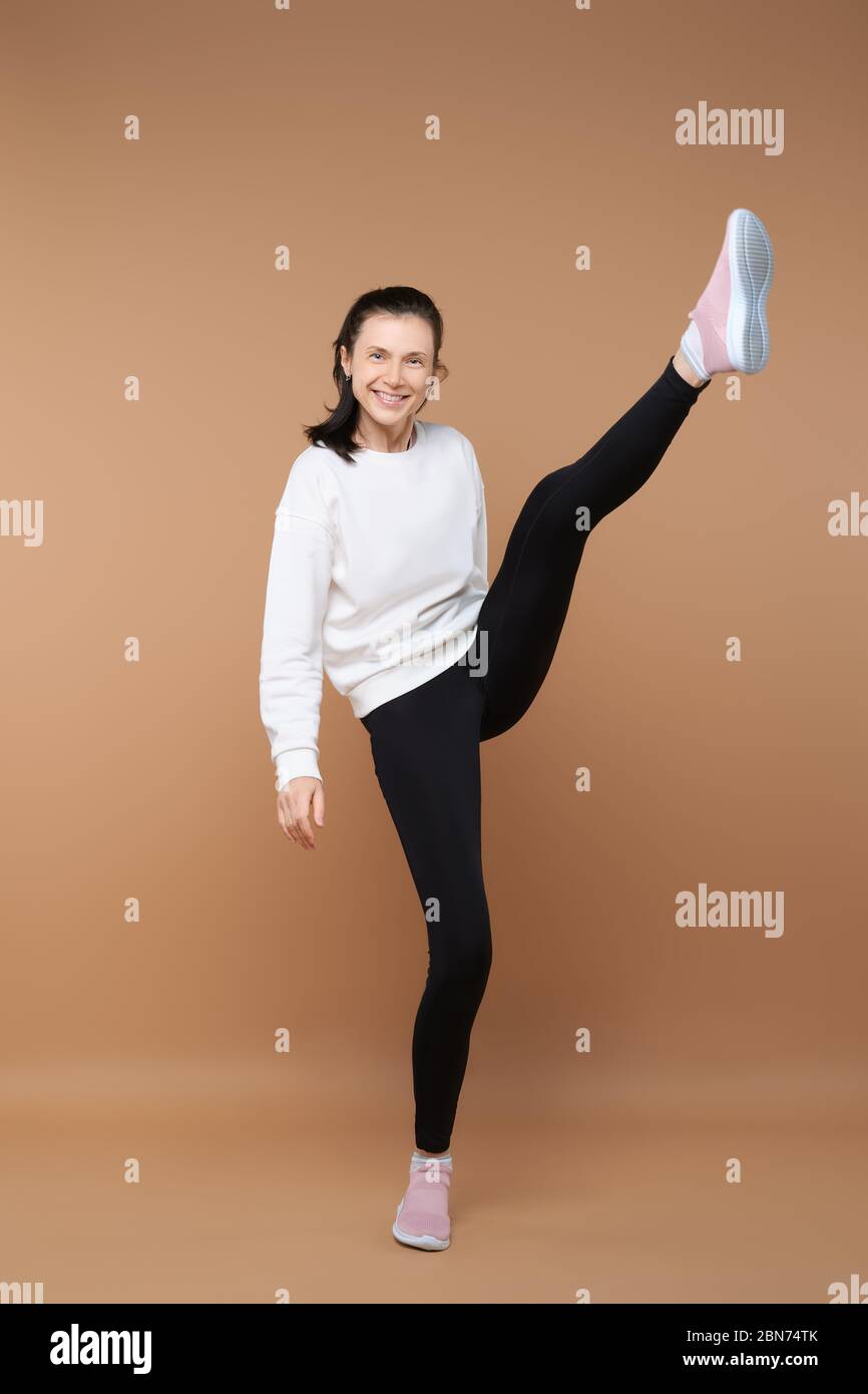 Sportliche Frau, die ein Bein im Studio hochstreckt Stockfoto