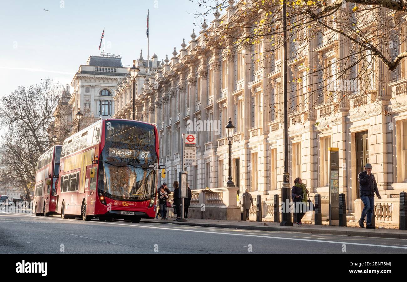 Rote Londoner Doppeldeckerbusse parkten vor dem Kabinettsgebäude in Whitehall, einem von britischen Regierungsgebäuden dominierten Gebiet. Stockfoto