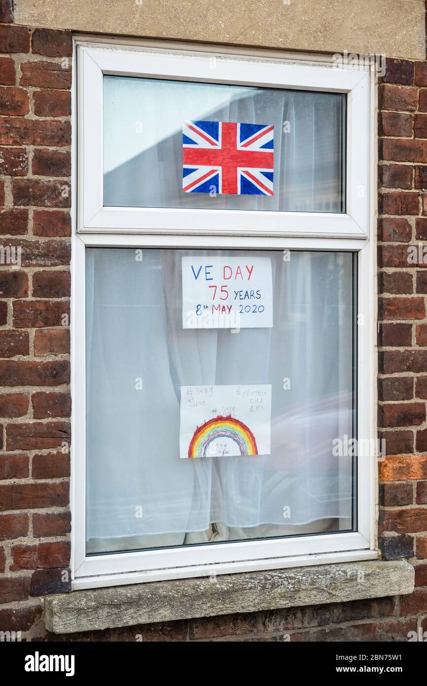 Eine Union Jack Flagge und hausgemachte Schilder in einem Fenster zum 75. Jahrestag des VE Day und zur Unterstützung der NHS, Großbritannien Stockfoto