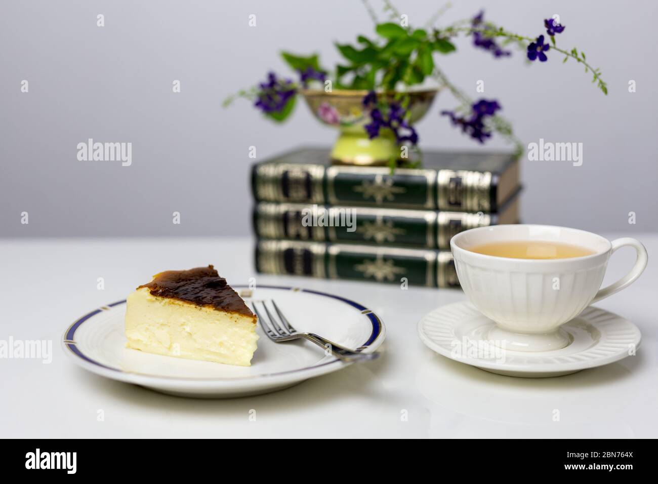 Teatime mit Scheibe baskischem, gebrannten Käsekuchen und einer Tasse Tee auf dem Tisch. Stockfoto