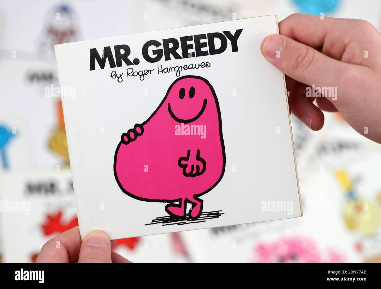 Ein Junge, der das Buch Mr Men lesen möchte, Mr Greedy von Roger Hargreaves Stockfoto