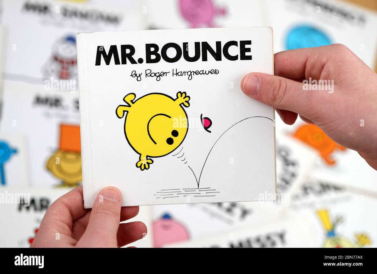 Ein Junge, der das Buch Mr Men lesen möchte, Mr Bounce von Roger Hargreaves Stockfoto