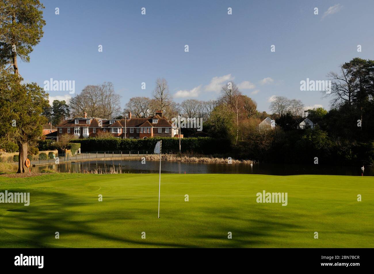 Blick über 18th Green zu Teich und Häusern, Woking Golf Club, Woking, Surrey, England Stockfoto