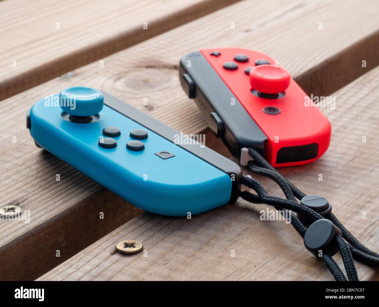 Mai 2020, UK: Nintendo Switch Joy con Controller rot und blau Neon im Freien auf Holztisch Stockfoto