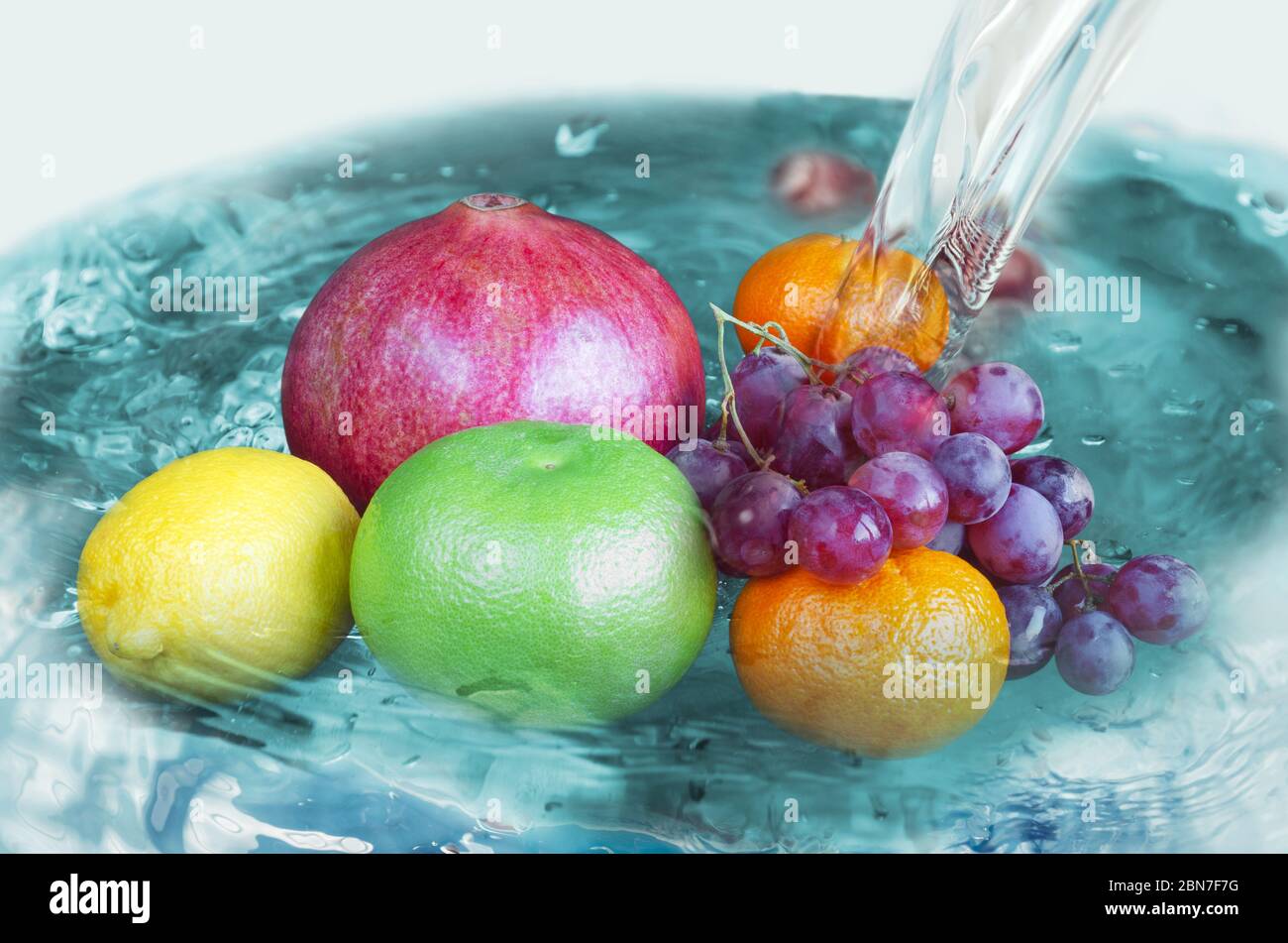 Verschiedene Früchte im Wasser unter dem Waschstrahl Stockfoto