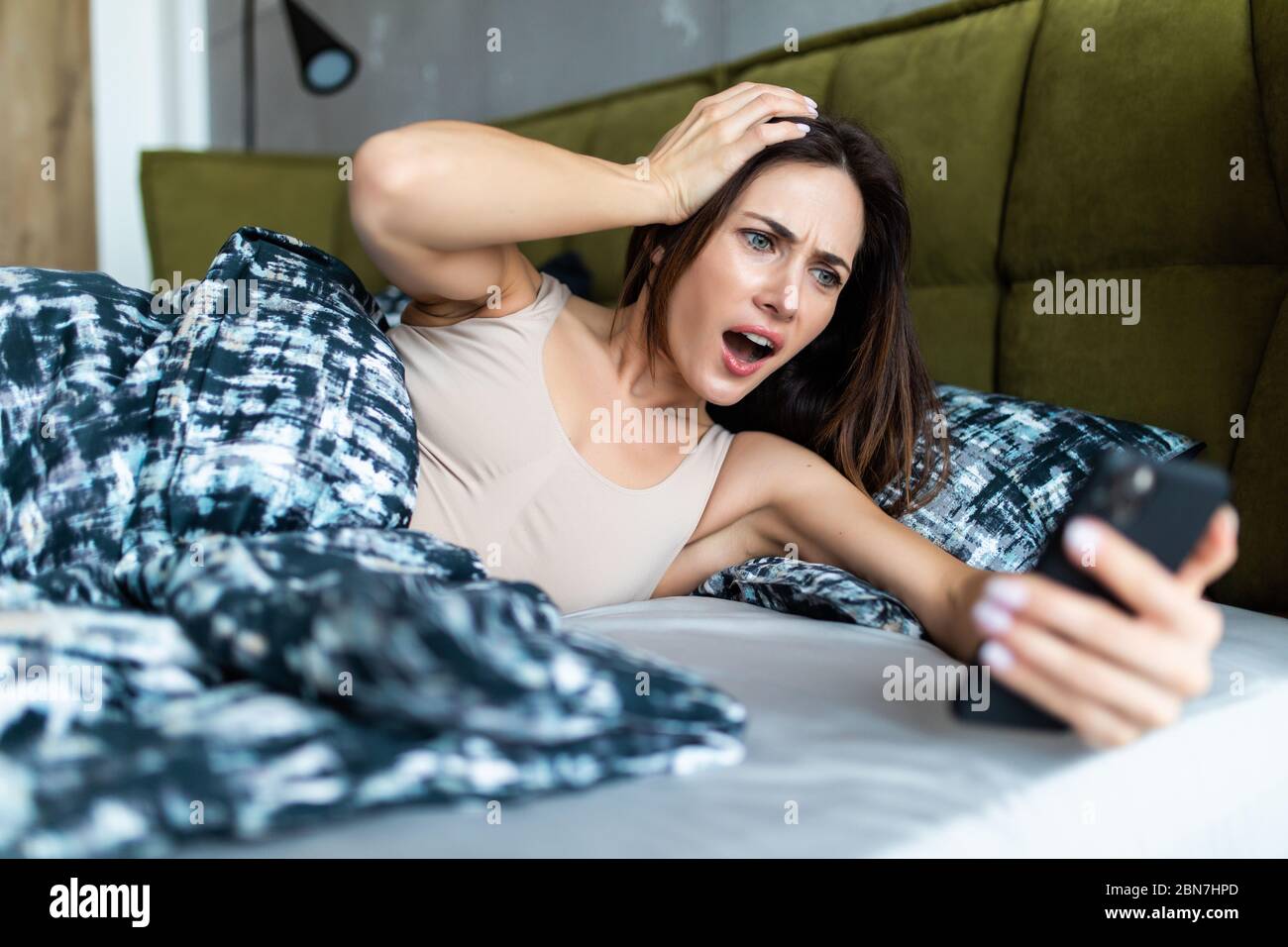 Attraktive junge Frau verpasste das Klingeln des Weckers und haben das Erwachen verschlafen und sind spät, reagierend in Schrecken zu der Zeit. Lustige Gesichtsausdruck Stockfoto