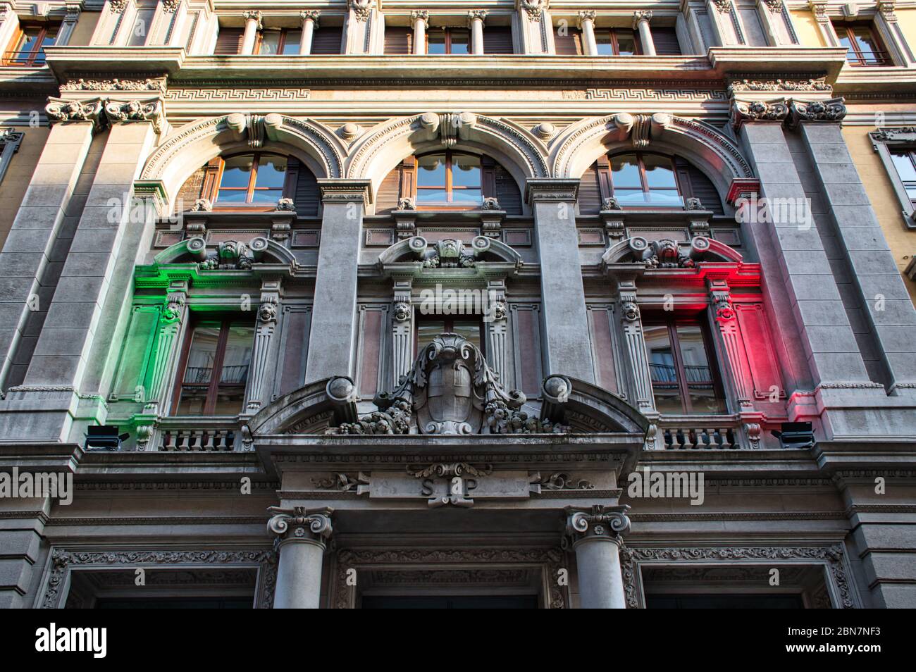 Mailand, Italien 05.12.2020: Eine traditionelle alte verzierte Fassade mit grünen, weißen und roten Lichtern, die die Nationalfarben Italiens darstellen Stockfoto