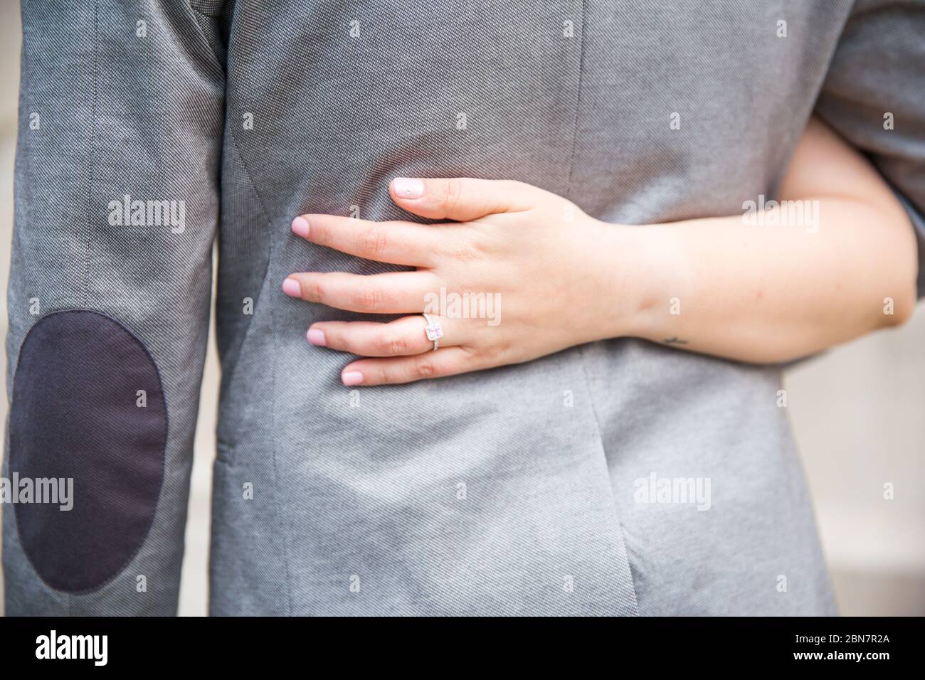 Mann und Frau halten sich an der Taille und zeigen den Hochzeitsring Stockfoto