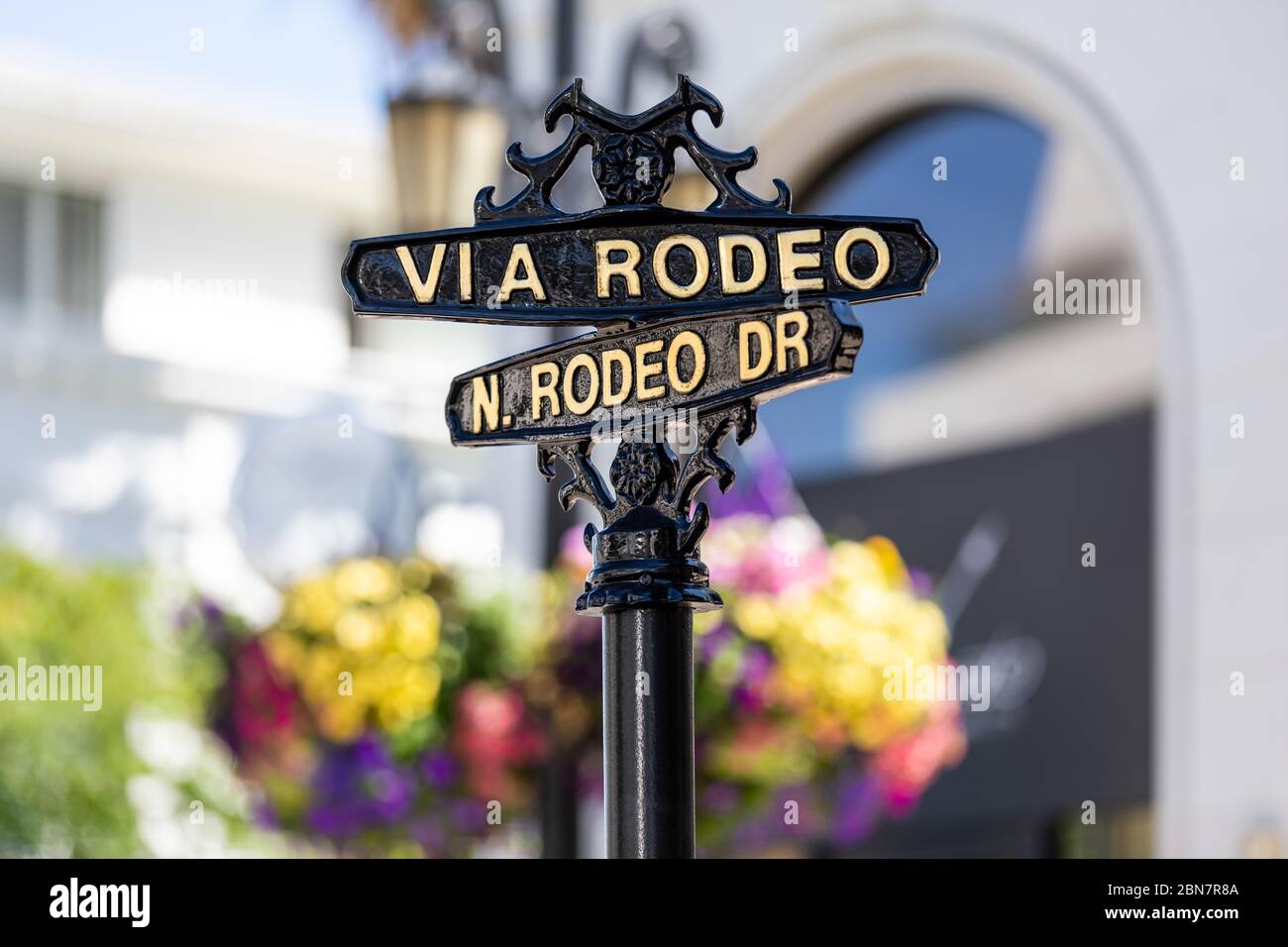 Symmetrische Nahaufnahme eines ikonischen schwarzen Bronzemarkens zwischen Rodeo Drive und Via Rodeo vor einem farbenfrohen Bokeh-Hintergrund Stockfoto