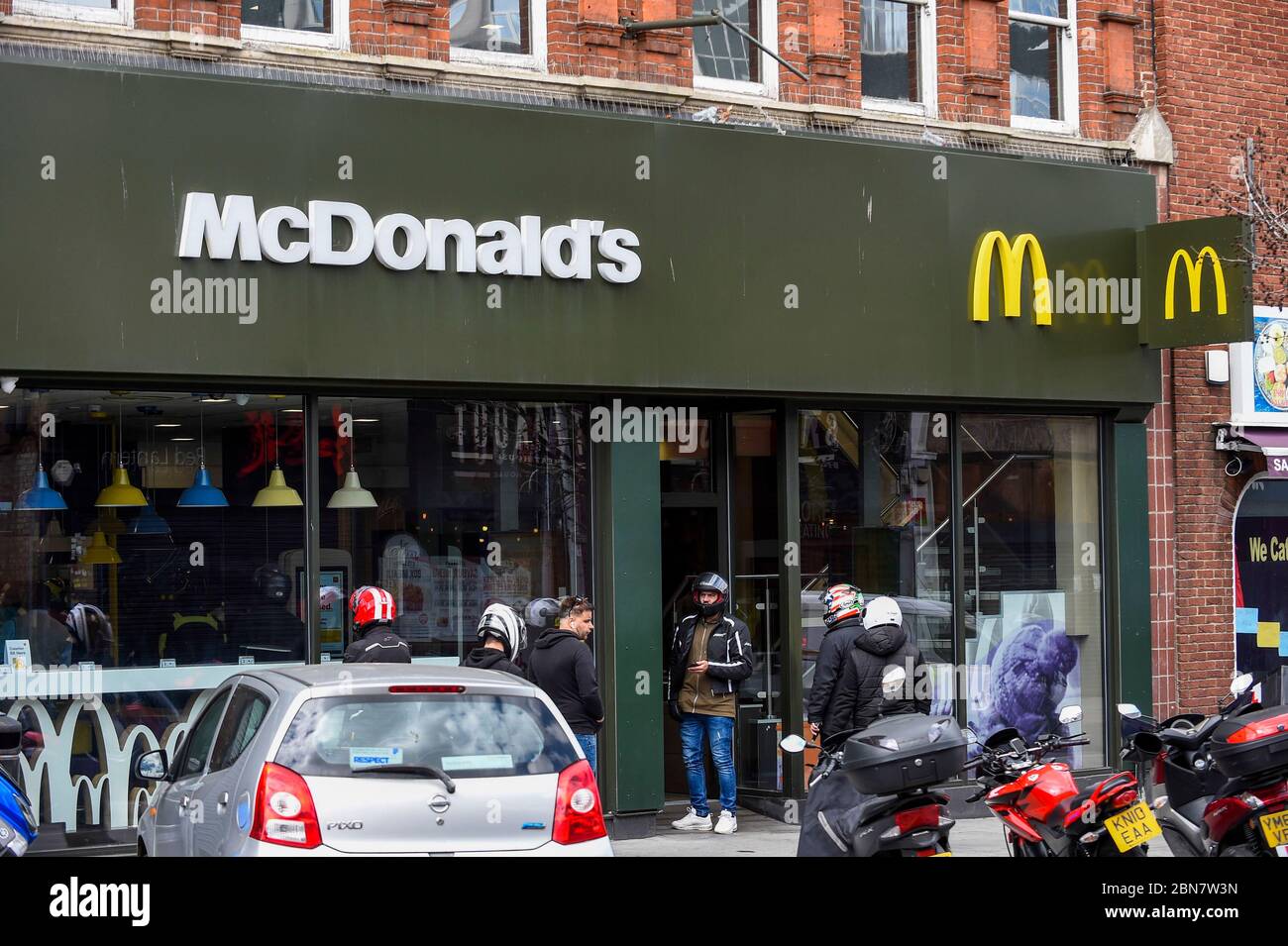 London, Großbritannien. 13 Mai 2020. Lieferfahrer warten auf Bestellungen, da das McDonald's Fast-Food-Restaurant in Harrow während der laufenden Coronavirus-Pandemie für „McDelivery“ wieder eröffnet wird. Das Restaurant ist eines von 14 in Großbritannien, das die Kette teilweise wieder eröffnet, mit einer begrenzten Speisekarte und Lieferung nur. Die Lieferung erfolgt durch Dritte wie Uber Eats und Deliveroo. Kredit: Stephen Chung / Alamy Live News Stockfoto