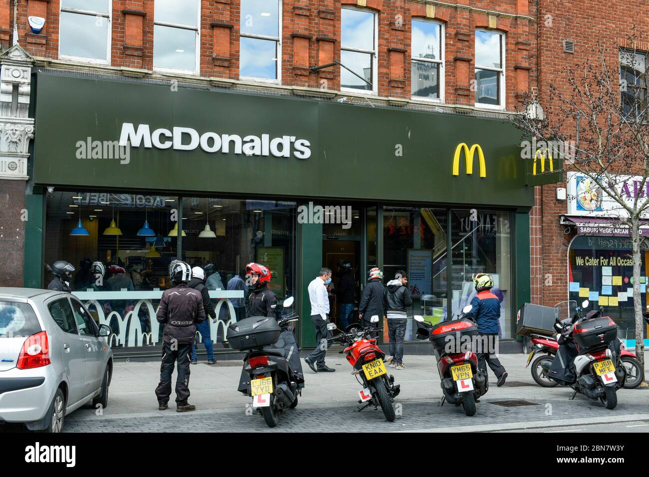 London, Großbritannien. 13 Mai 2020. Lieferfahrer warten auf Bestellungen, da das McDonald's Fast-Food-Restaurant in Harrow während der laufenden Coronavirus-Pandemie für „McDelivery“ wieder eröffnet wird. Das Restaurant ist eines von 14 in Großbritannien, das die Kette teilweise wieder eröffnet, mit einer begrenzten Speisekarte und Lieferung nur. Die Lieferung erfolgt durch Dritte wie Uber Eats und Deliveroo. Kredit: Stephen Chung / Alamy Live News Stockfoto