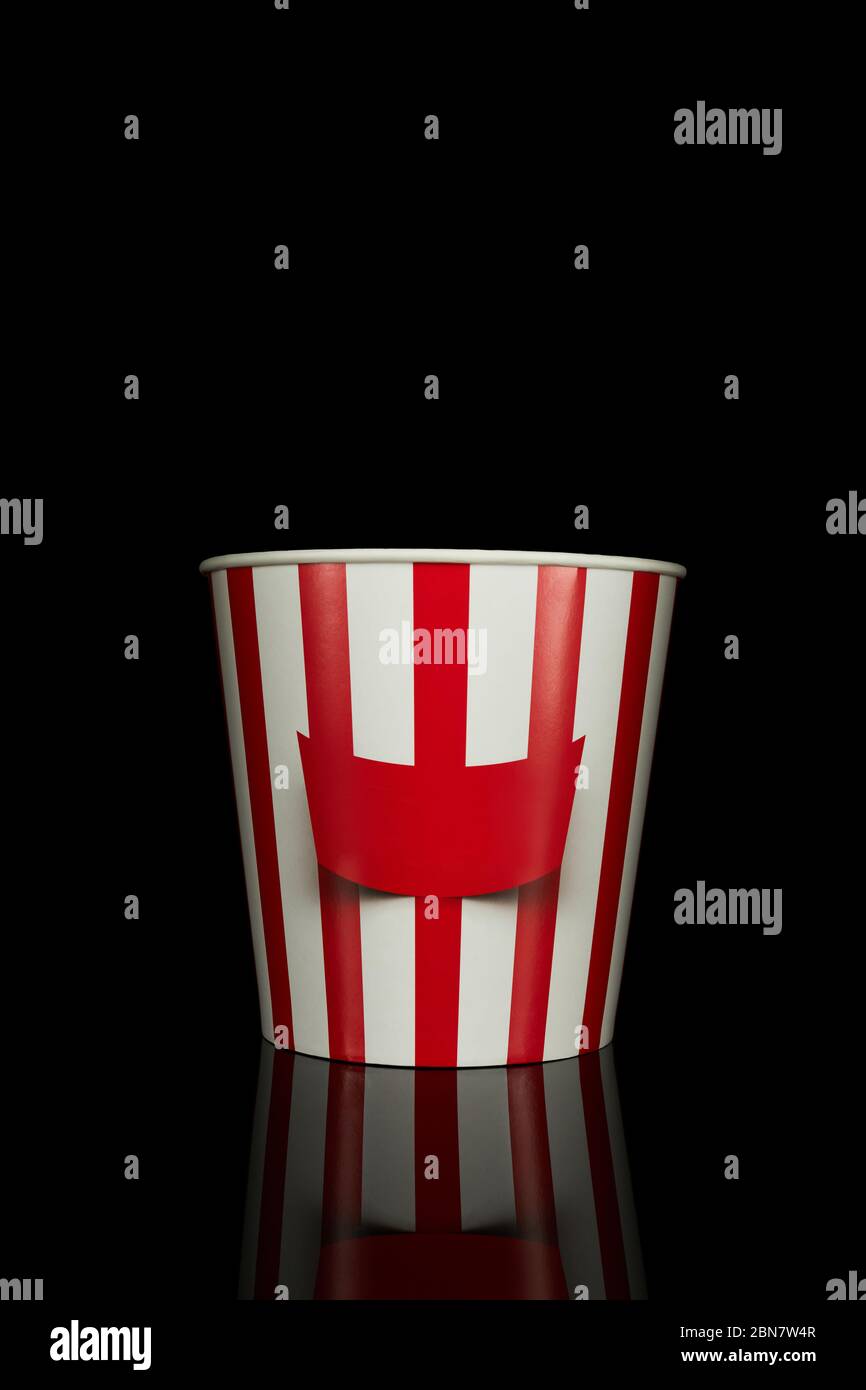 Leerer klassischer rot-weißer Papiereimer mit Streifen für Popcorn isoliert auf schwarzem Hintergrund. Stockfoto