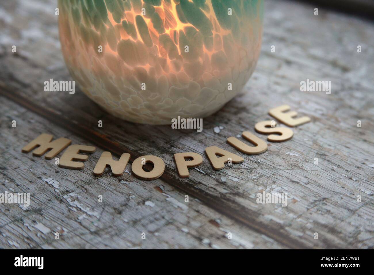 Wechseljahre in Holzbuchstaben gegen Flammeneffekt Kerzenvase geschrieben Stockfoto