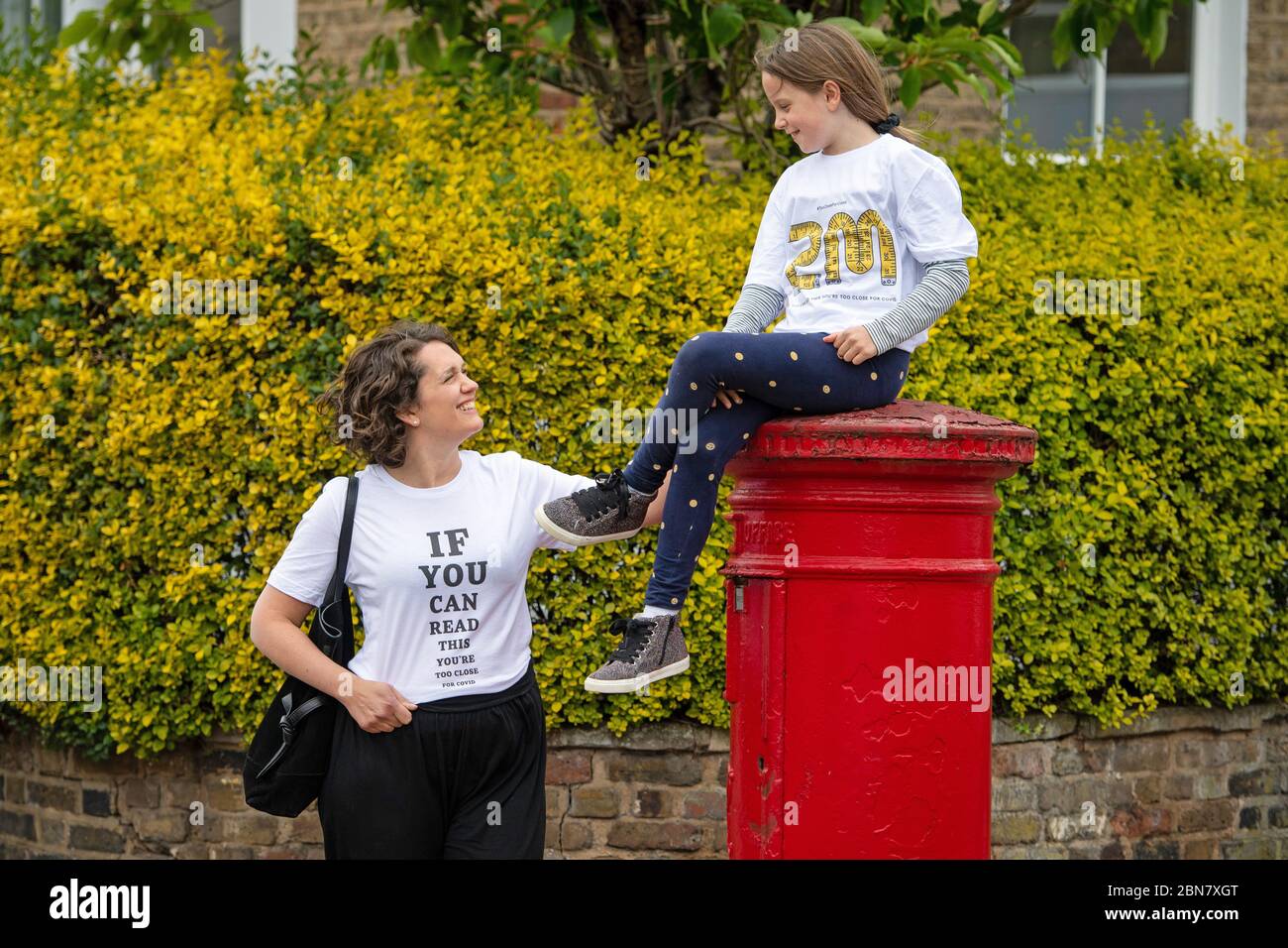 Fiona und ihre Tochter Lola aus London tragen T-Shirts mit dem Slogan: „Wenn Sie dies lesen können, sind Sie zu nahe an COVID“, die vom globalen Unternehmen für die Markenumwandlung FutureBrand als gemeinnützige Initiative ins Leben gerufen wurden, um die wichtigsten Richtlinien für soziale Distanzierung zu stärken, während die Nation aus der Sperrung der Coronavirus-Pandemie herauskommt. Stockfoto