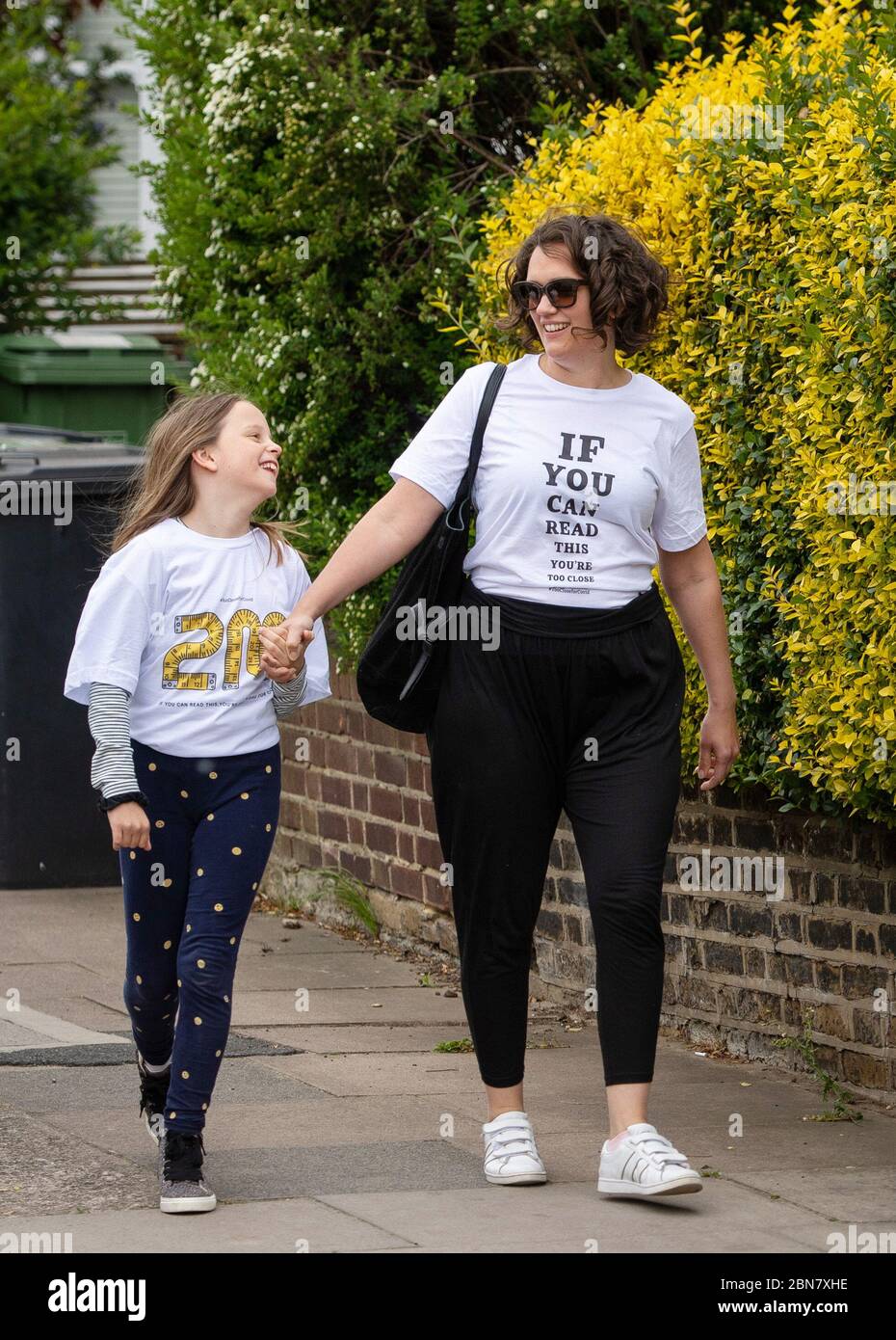 Fiona und ihre Tochter Lola aus London tragen T-Shirts mit dem Slogan: „Wenn Sie dies lesen können, sind Sie zu nahe für COVID“, die vom globalen Unternehmen zur Markenumwandlung FutureBrand als gemeinnützige Initiative ins Leben gerufen wurden, um wichtige Richtlinien zur sozialen Distanzierung zu verstärken, während die Nation aus der Blockierung der Coronavirus-Pandemie herauskommt. Stockfoto